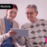 Pessoa jovem mostrando algo em tablet para pessoa idosa.