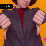Pessoa de terno apontando os polegares para baixo.