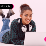Adolescente sorrindo enquanto olha para notebook.
