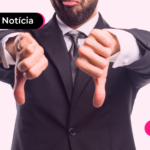 Pessoa de terno apontando os polegares para baixo.