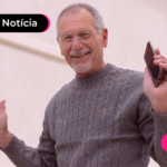 Pessoa idosa segurando celular com expressão feliz.