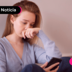 Pessoa com expressão triste olhando para celular.