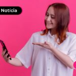 Jovem sorrindo enquanto usa celular para ler notícia sobre PIS/Pasep de 2025.