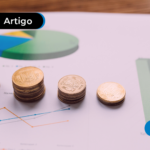Moedas em cima de papéis com gráficos com dados econômicos.