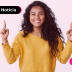 Mulher apontando os dois indicadores para cima e sorrindo.