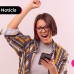 Mulher segurando celular e comemorando.