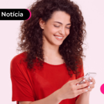 Mulher sorrindo enquanto olha para celular.
