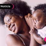 Pessoa com criança no colo e expressão feliz.