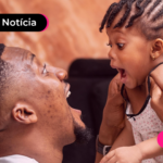 Homem segurando criança com expressão feliz.