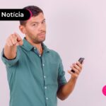 Pessoa com expressão de alerta segurando um celular.