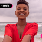 Mulher em praia com expressão feliz.