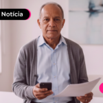 Homem idoso segurando celular e papéis.