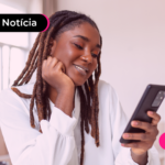Mulher olhando para celular com expressão feliz.