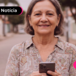 Pessoa de idade sorrindo enquanto usa celular para ler notícia sobre desbloqueio do INSS que libera novo valor de empréstimo.