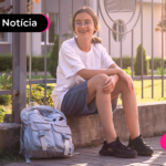 Estudante sentada em calçada.