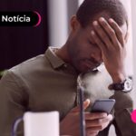 Homem olhando desapontado para celular.