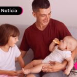Homem abraçando duas crianças.