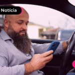 Homem dentro de carro olhando para celular.