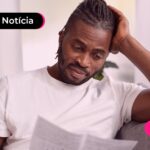 Homem olhando para papel com expressão triste.