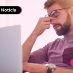 Homem olhando para computador com mão no rosto.