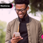 Homem olhando para celular com expressão feliz.