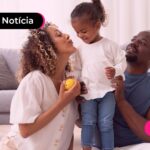 Mulher e homem abraçando criança em casa.