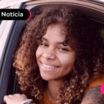Mulher em carro sorrindo.
