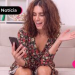 Mulher olhando para celular com expressão feliz.