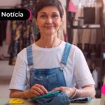 Mulher costurando jeans sorrindo.