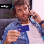 Homem no telefone com cartão na mão.