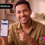Homem apontando para celular com expressão feliz.