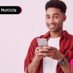Jovem usando celular para ler notícia sobre consulta do primeiro lote da restituição.