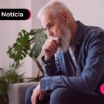 Homem idoso em sofá pensativo.