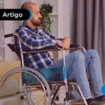 Homem sentado em uma cadeiras de rodas em um ambiente interno.
