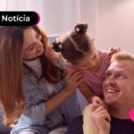Família abraçada com criança em sofá.