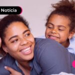 Criança deitada com mãe em sofá.