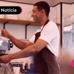 Homem feliz trabalhando em cafeteria.
