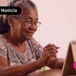 Mulher idosa olhando para calendário com expressão feliz.