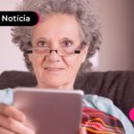 Idosa de óculos lendo sobre dificuldade com biometria do INSS.