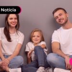 Criança ao lado de pais em casa.