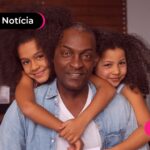 Homem sendo abraçado por duas crianças.
