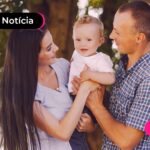 Criança abraçada com pais em parque.
