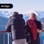 Casal de costas observando uma paisagem de montanhas cobertas de neve em Bariloche.