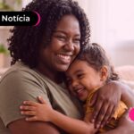 Mãe e filha tendo um momento de afeto sentadas em um sófa.