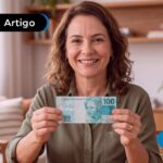 Mulher sentada em uma sala segurando uma nota de 100 reais.