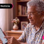 Idoso de cabelos grisalhos sentado em uma mesa de estar.