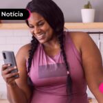 Mulher negra de tranças olhando para o celular.