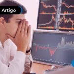 Homem de blusa social branca olhando para um computador.