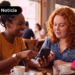 Duas mulheres sentadas olhando para um celular.