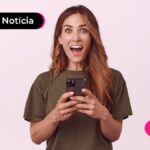 Jovem sorrindo com expressão de surpresa após ler notícia sobre pagamento do abono salarial.